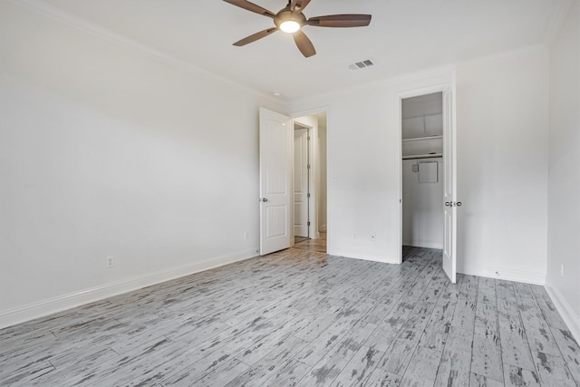 unfurnished bedroom with baseboards, light wood finished floors, visible vents, and crown molding