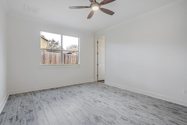 spare room featuring baseboards, crown molding, visible vents, and wood finished floors