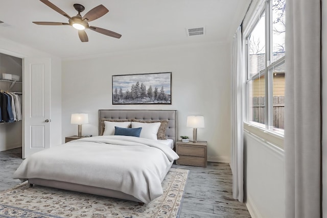 bedroom featuring ornamental molding, visible vents, baseboards, and wood finished floors