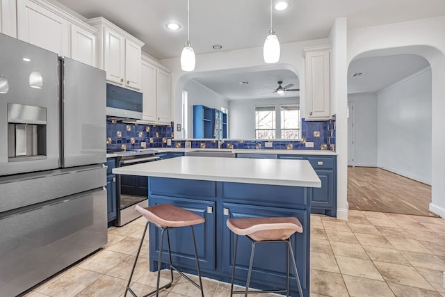 kitchen with white cabinetry, appliances with stainless steel finishes, blue cabinetry, and a kitchen bar