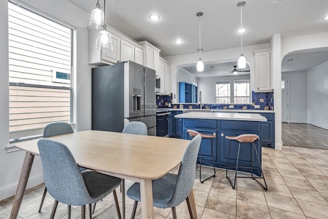 kitchen featuring blue cabinets, arched walkways, light countertops, and stainless steel fridge with ice dispenser