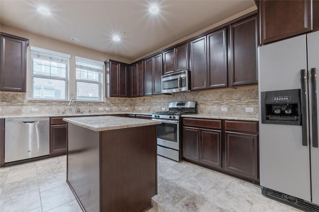 kitchen featuring backsplash, dark brown cabinets, stainless steel appliances, sink, and a kitchen island