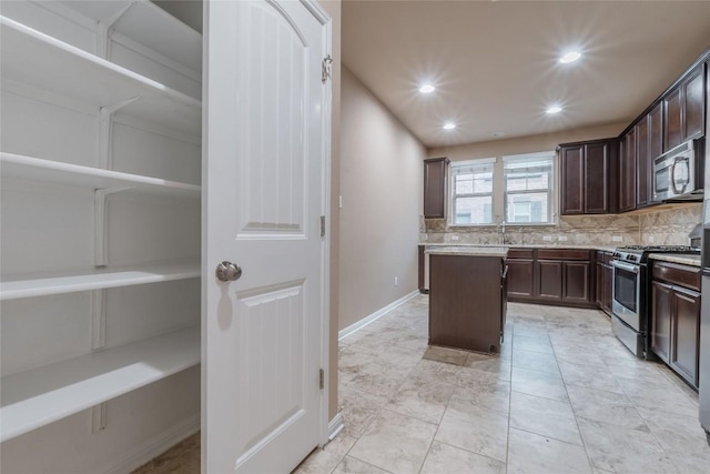 kitchen featuring decorative backsplash, appliances with stainless steel finishes, dark brown cabinetry, and a center island