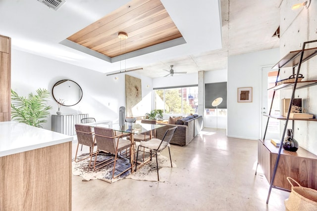 dining space with ceiling fan and a raised ceiling