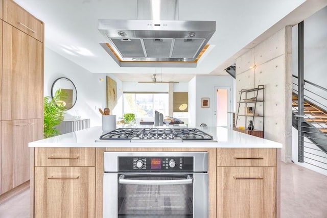 kitchen with light brown cabinetry, a kitchen island, range hood, and appliances with stainless steel finishes