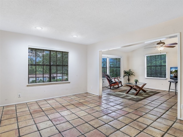 interior space featuring vaulted ceiling, ceiling fan, and a textured ceiling