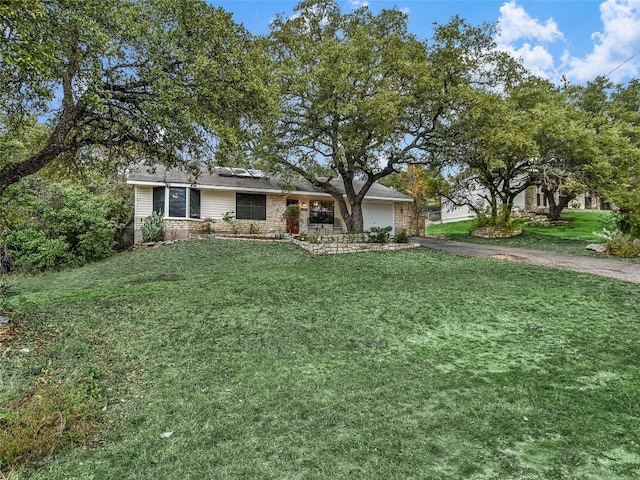 ranch-style home with a garage, a front yard, and solar panels