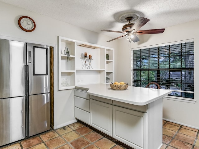 kitchen featuring ceiling fan, stainless steel fridge, kitchen peninsula, and a textured ceiling