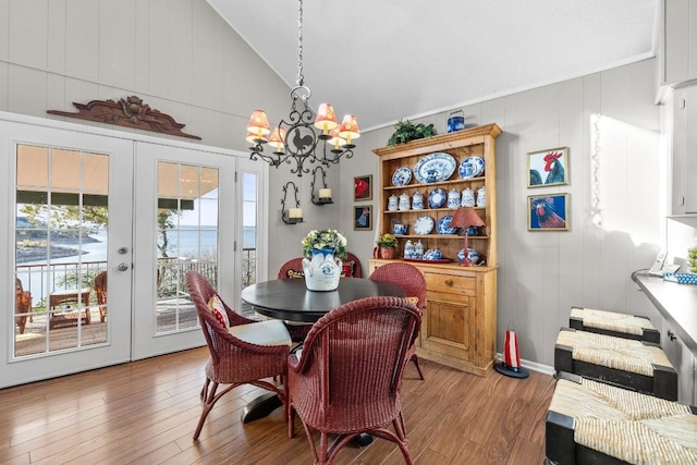 dining room with a water view, french doors, an inviting chandelier, and light wood-type flooring