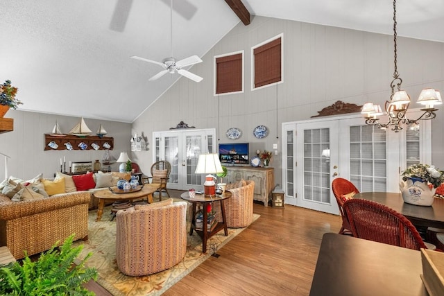 living room with lofted ceiling with beams, wood-type flooring, ceiling fan with notable chandelier, and french doors