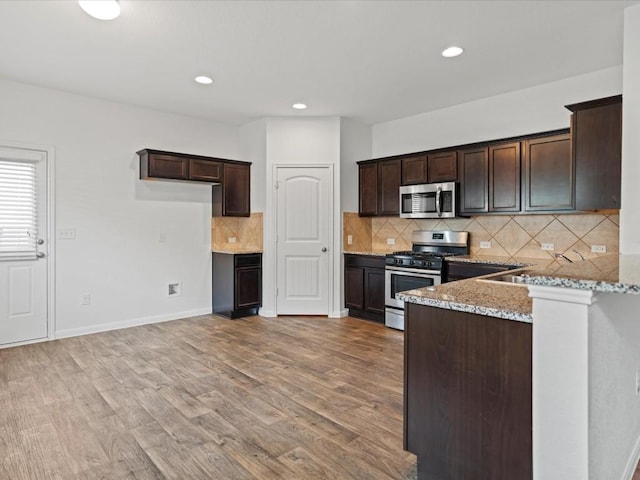 kitchen with dark brown cabinetry, light stone counters, light hardwood / wood-style flooring, and stainless steel appliances