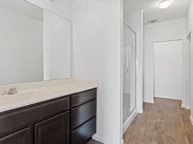 bathroom with hardwood / wood-style flooring, vanity, and walk in shower