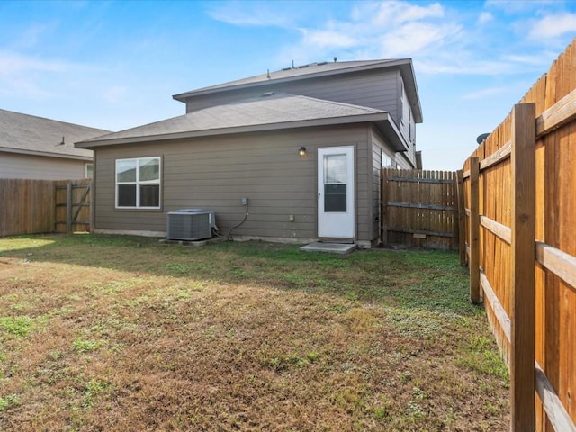 back of property with central AC unit and a lawn