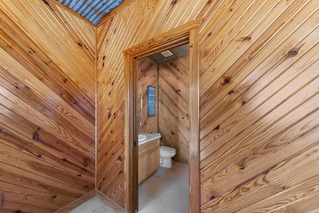 bathroom with wood walls, vanity, and toilet