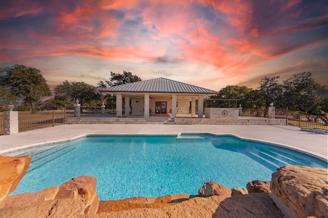 pool at dusk featuring a patio