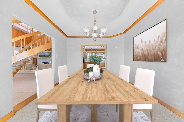 dining space featuring a chandelier, carpet flooring, a stone fireplace, and crown molding