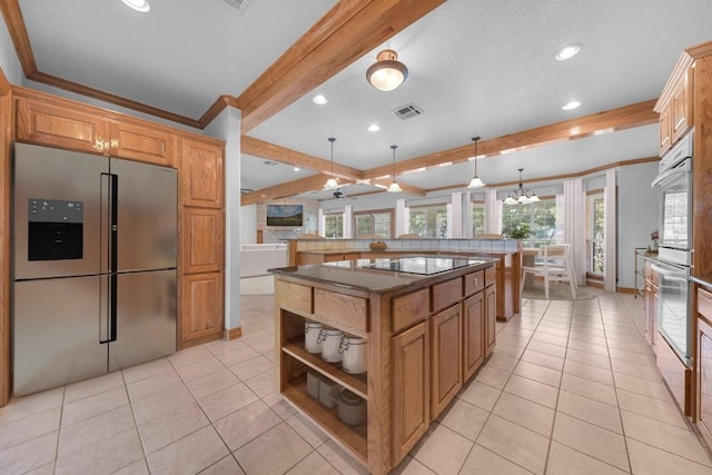 kitchen featuring beam ceiling, a center island, stainless steel appliances, a notable chandelier, and decorative light fixtures