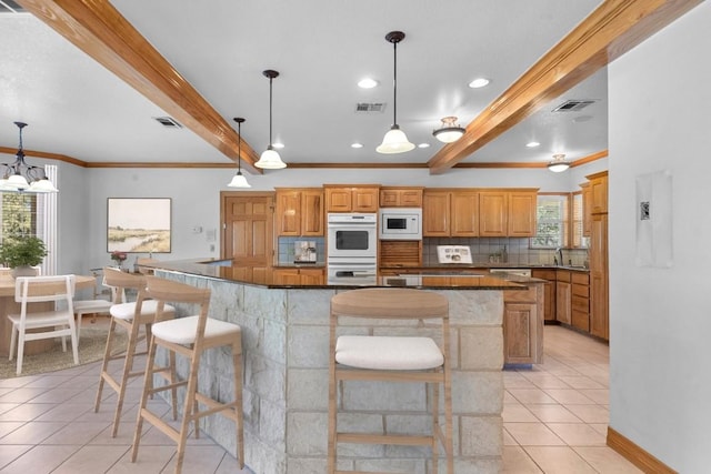 kitchen with white appliances, a kitchen breakfast bar, hanging light fixtures, light tile patterned floors, and beam ceiling