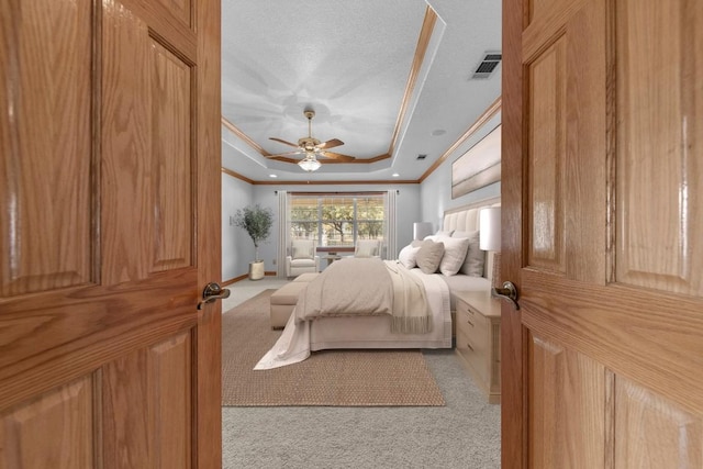 carpeted bedroom with a textured ceiling, ceiling fan, a raised ceiling, and crown molding