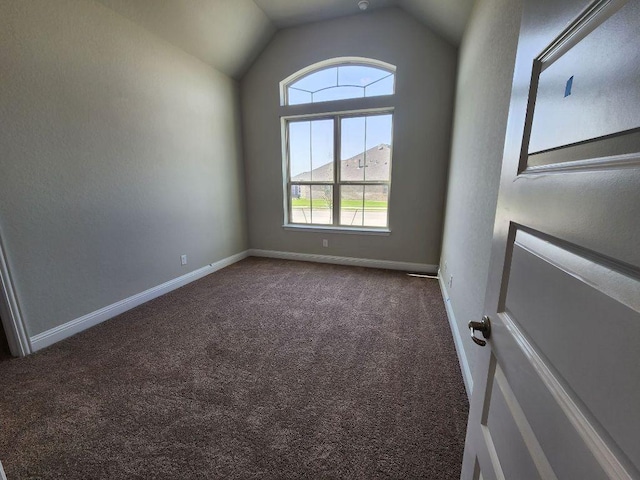 unfurnished room with vaulted ceiling, dark carpet, and baseboards