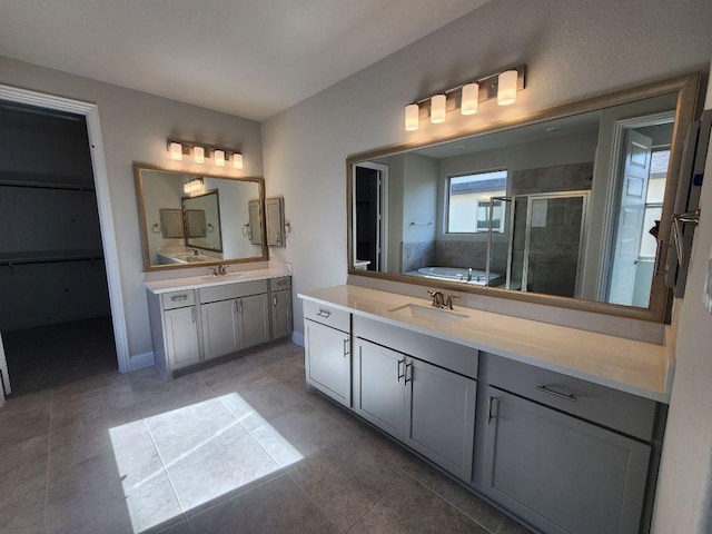 full bath featuring a bath, a shower stall, two vanities, and a sink