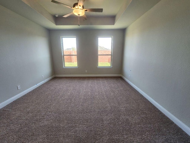 spare room featuring ceiling fan, carpet, a raised ceiling, and baseboards