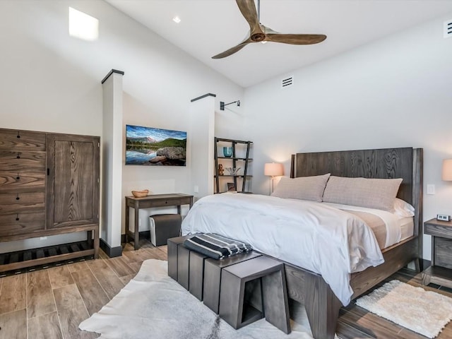 bedroom featuring ceiling fan, a high ceiling, and light hardwood / wood-style flooring