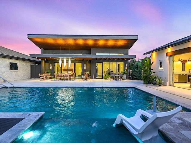 pool at dusk featuring a patio and ceiling fan