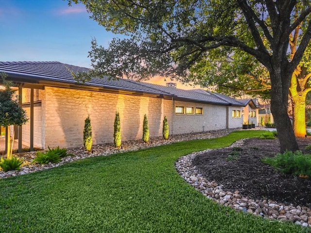 property exterior at dusk featuring a lawn