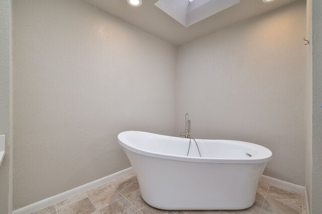 bathroom with a washtub and a skylight