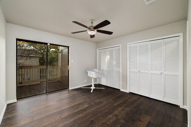 unfurnished bedroom featuring access to outside, dark wood-type flooring, ceiling fan, and multiple closets