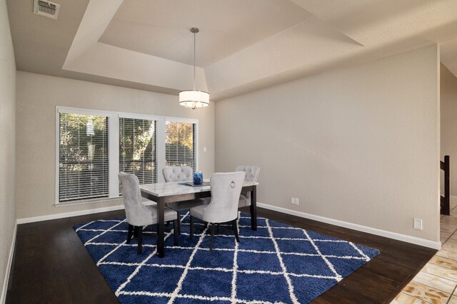 dining space featuring dark hardwood / wood-style floors and a raised ceiling