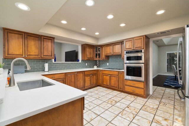 kitchen featuring decorative backsplash, kitchen peninsula, sink, and stainless steel appliances