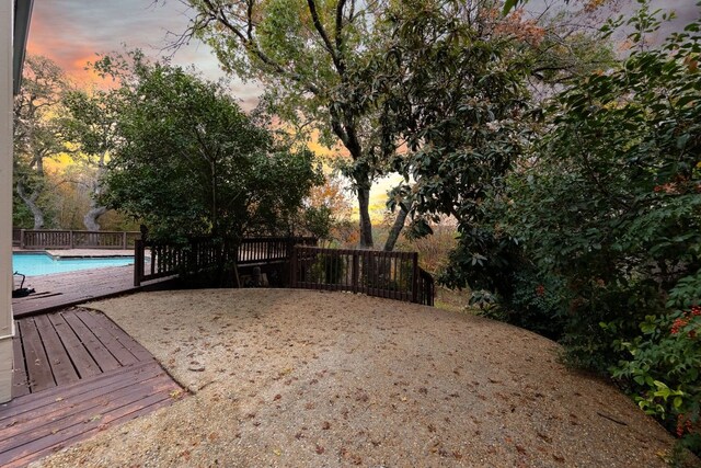 yard at dusk featuring a swimming pool side deck