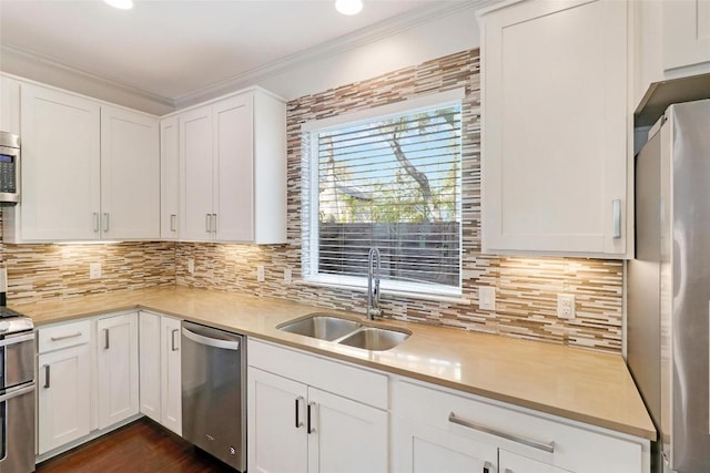 kitchen featuring white cabinets, crown molding, sink, and stainless steel appliances