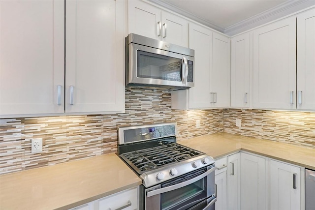 kitchen with white cabinets, appliances with stainless steel finishes, decorative backsplash, and crown molding