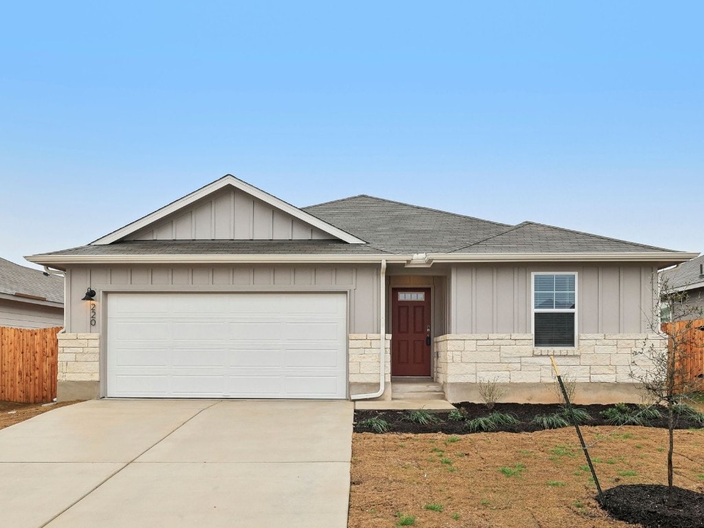 ranch-style home featuring driveway, stone siding, roof with shingles, an attached garage, and board and batten siding