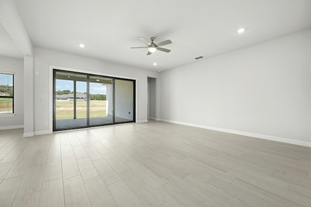 empty room with ceiling fan and light hardwood / wood-style flooring