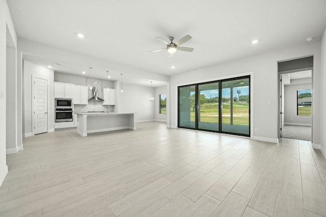 unfurnished living room featuring ceiling fan and light hardwood / wood-style flooring