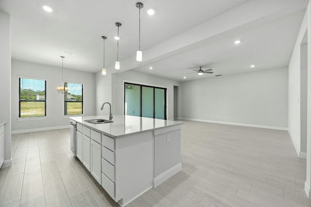 kitchen featuring white cabinetry, sink, pendant lighting, a kitchen island with sink, and ceiling fan with notable chandelier