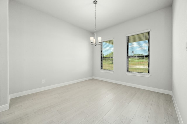 unfurnished room featuring a chandelier and light wood-type flooring