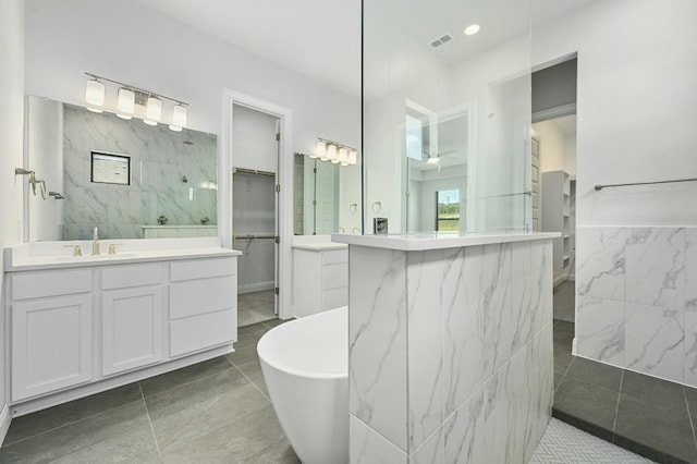 bathroom featuring tile patterned flooring, shower with separate bathtub, vanity, and tile walls