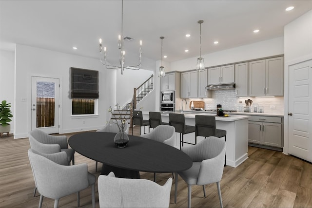 dining space with a chandelier, sink, and light hardwood / wood-style flooring