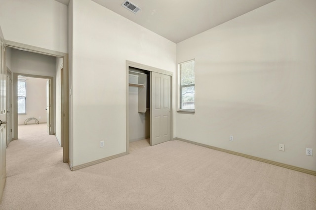 unfurnished bedroom with light colored carpet and a closet