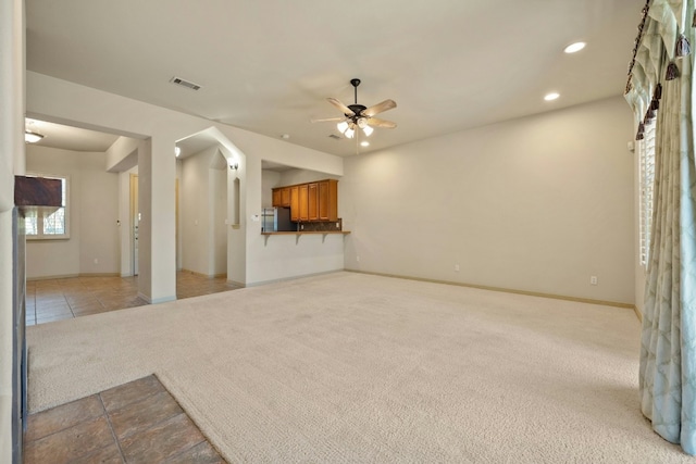 unfurnished living room featuring ceiling fan and light carpet