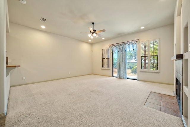 unfurnished living room featuring a fireplace, light colored carpet, and ceiling fan