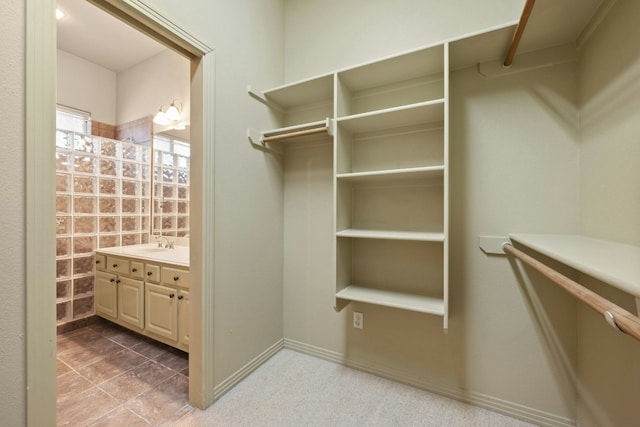 walk in closet with light tile patterned floors and sink