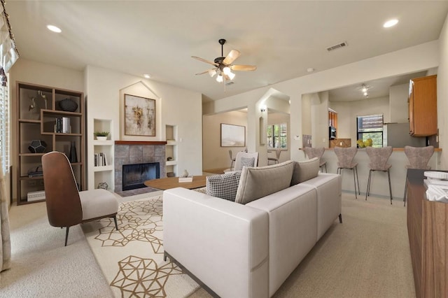 carpeted living room with a fireplace and ceiling fan