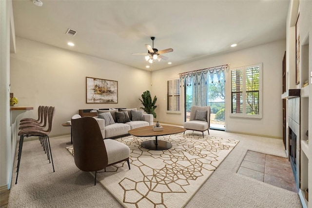 living room with light colored carpet, ceiling fan, and a tiled fireplace