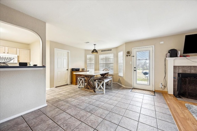 interior space with a tile fireplace, hanging light fixtures, and light wood-type flooring